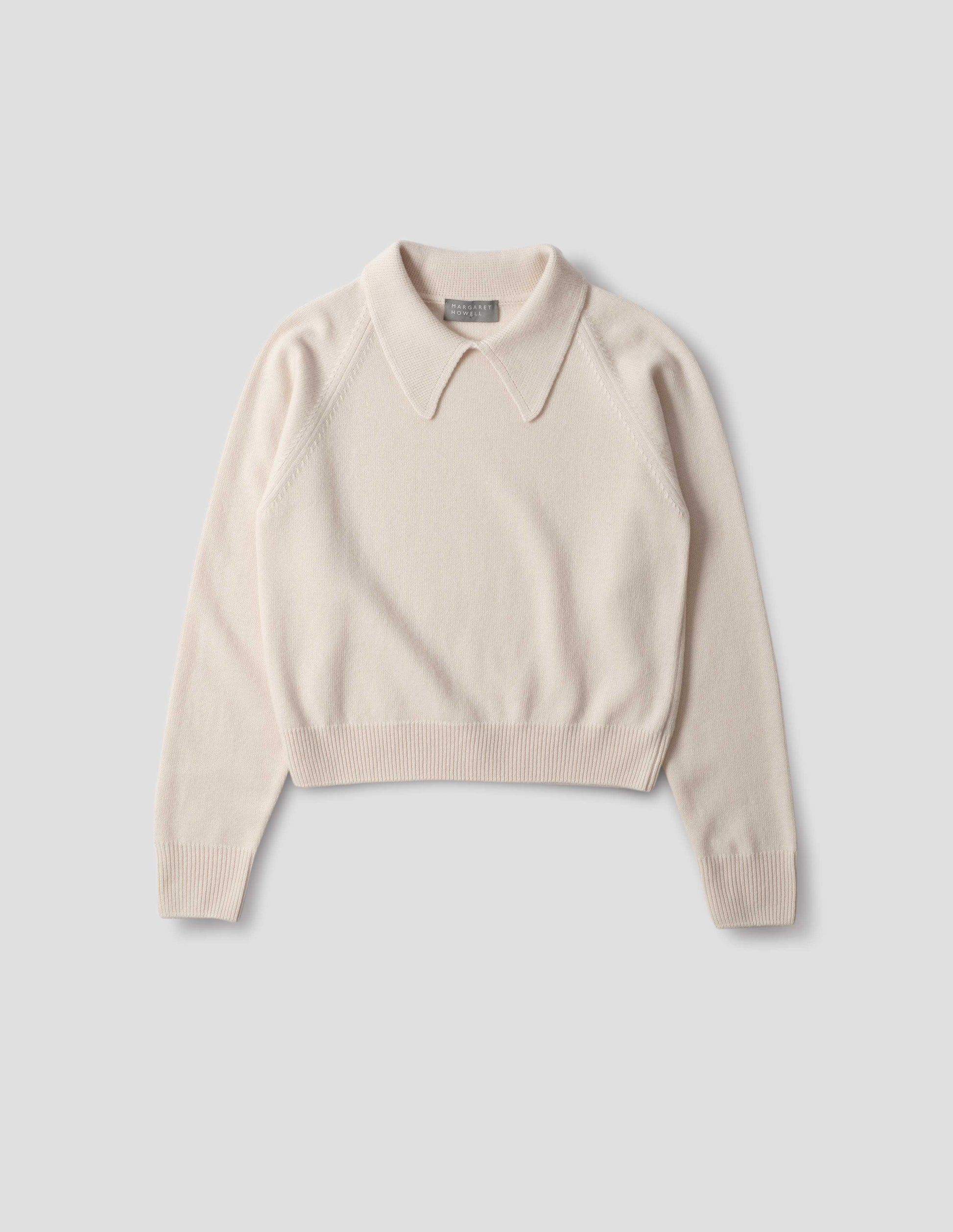 Light beige merino jumper with exaggerated collar, raglan sleeves, ribbed cuffs and hem. Front flat lay view.