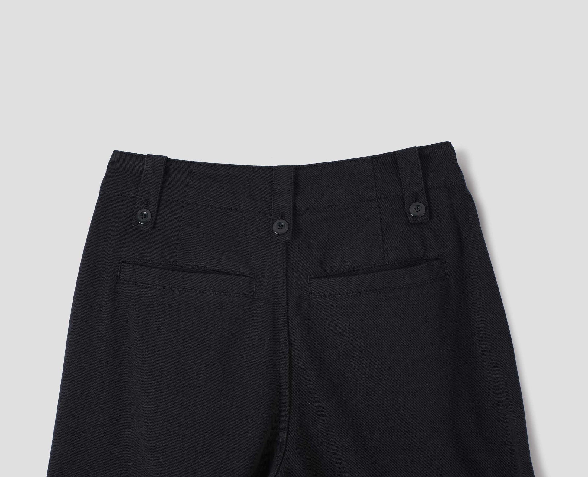 Black cotton tencel wide leg trousers with a button-fastening belt loops and back welt pockets, back flat lay view.