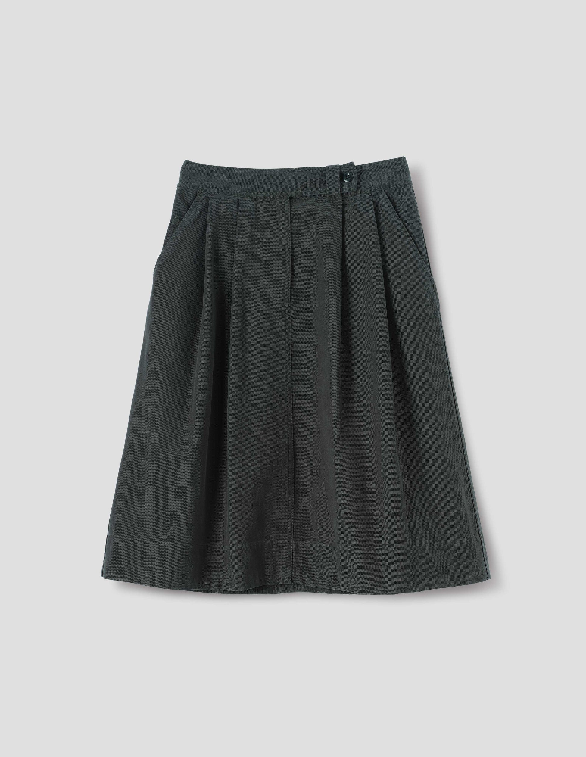 Dark green cotton skirt, with loop and button fastening, slant pockets and ticket pocket, front flat lay view.