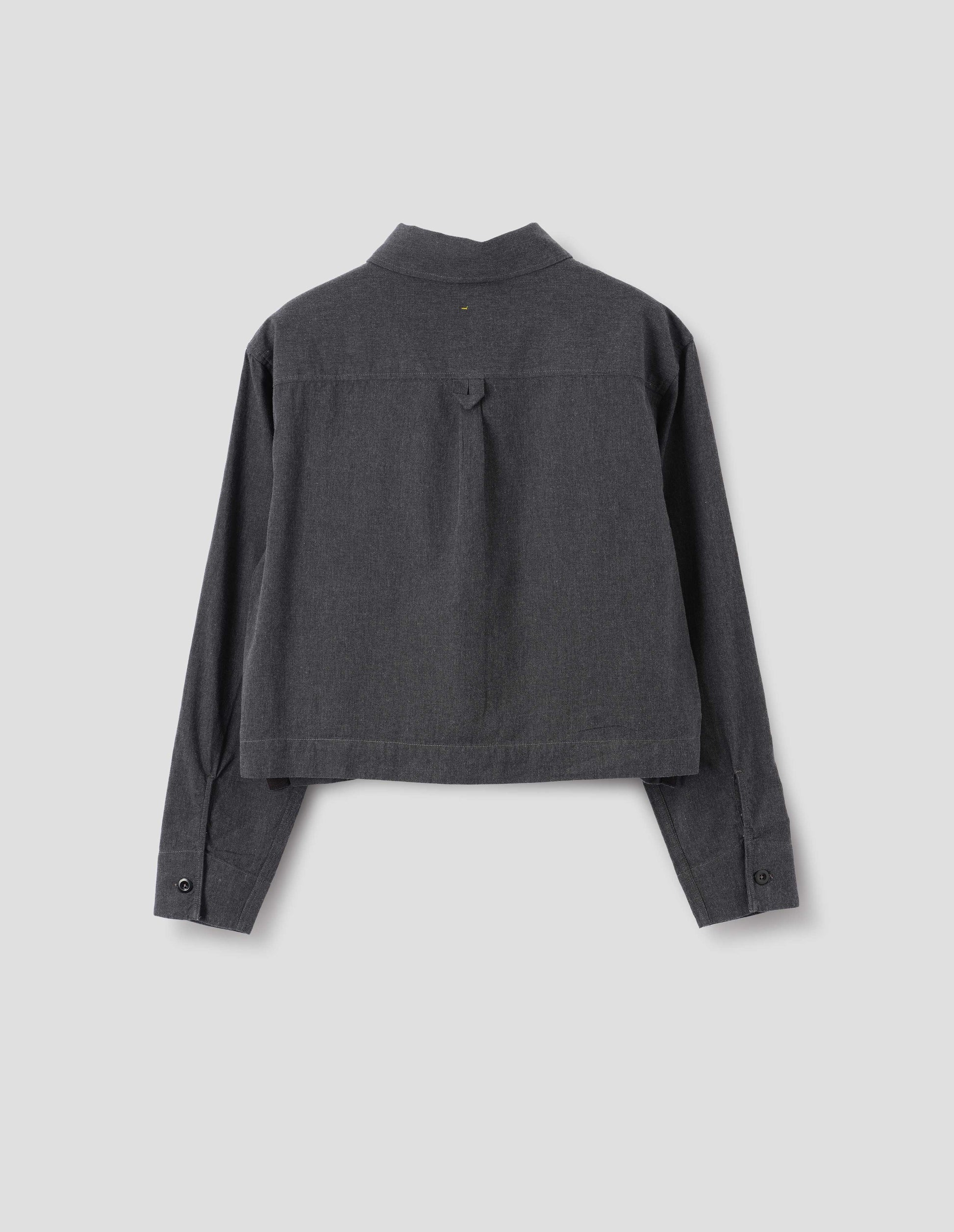 Dark grey cotton chambray shirt with grown-on cuffs, box pleat on back yoke and external hem loop detailing, front flat lay view.