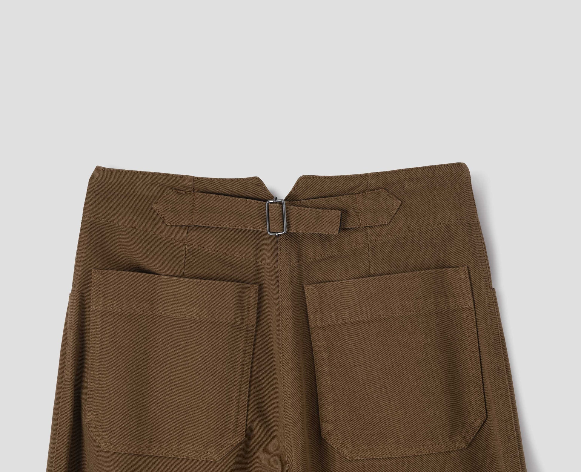 Brown cotton trousers, with patch back pockets and cinch waist adjuster, back flat lay view.
