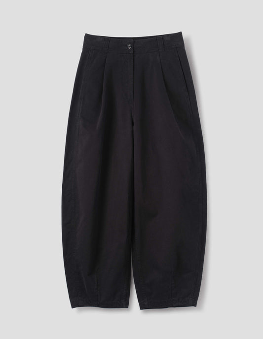 Black cotton trousers with a forward side seam and side seam pockets, deep single pleats at the front, darts at the hem, front flat lay view.