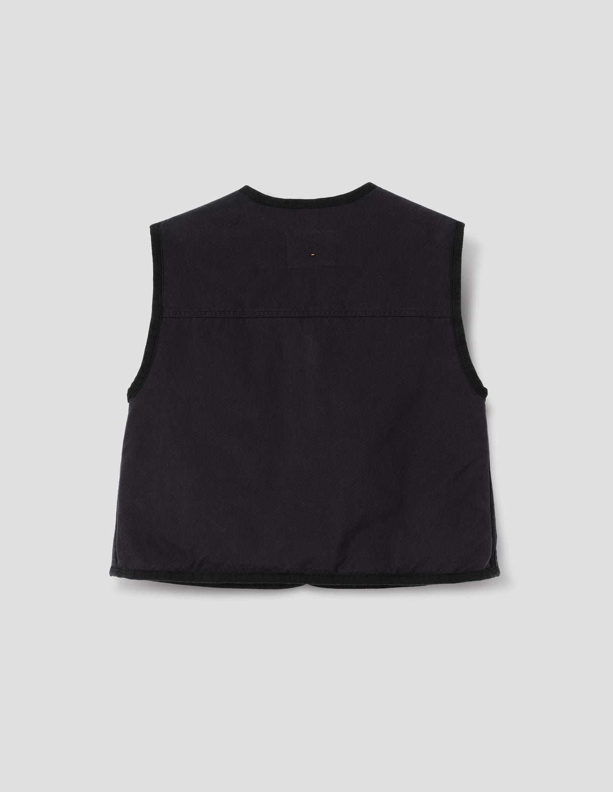 Black cotton twill sleeveless lightly padded liner with herringbone binding along edges and seam and back yoke with twin needle stitching, back flat lay view.