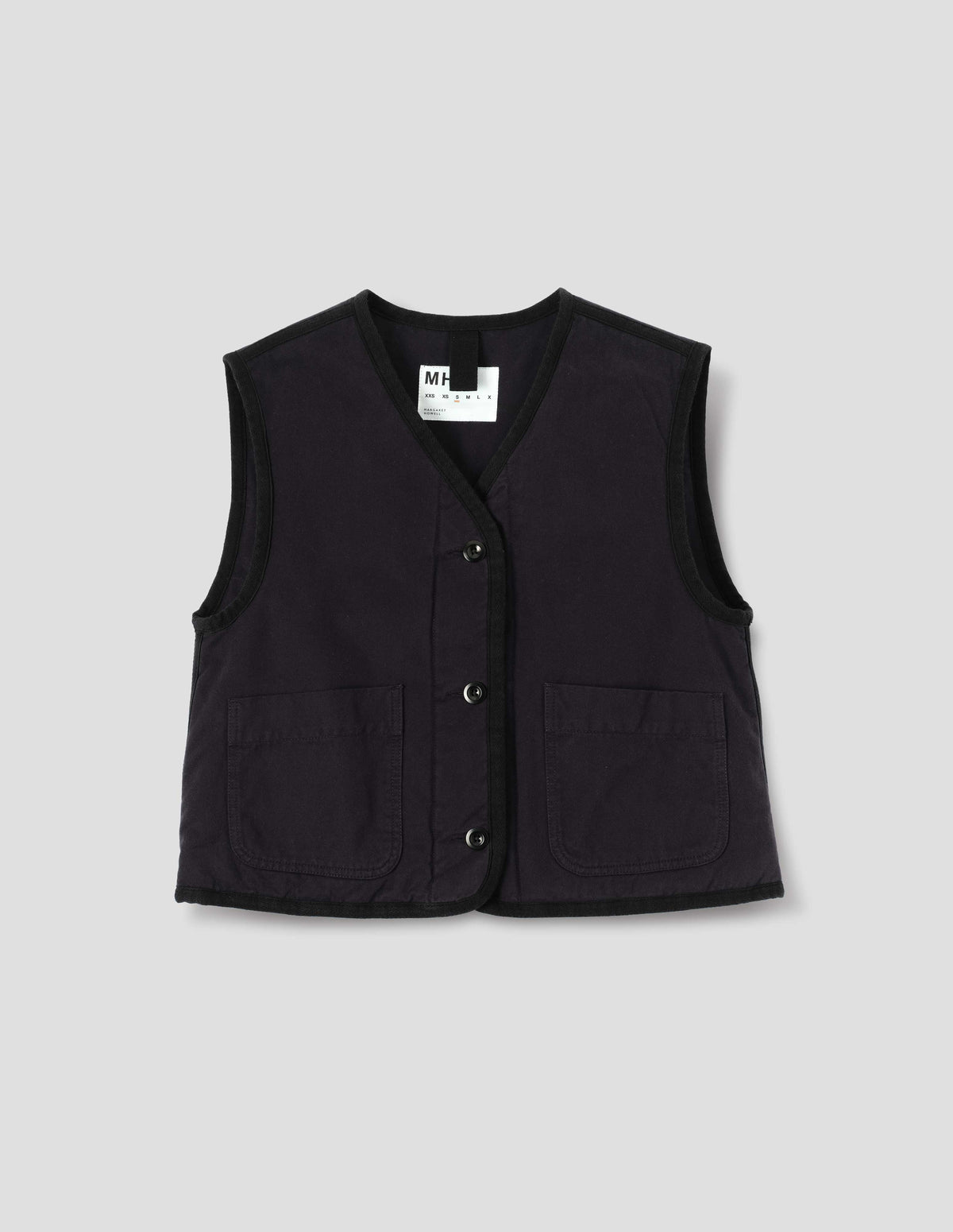 Black cotton twill sleeveless lightly padded liner with front patch pockets, and herringbone binding along edges and seam, front flat lay view.