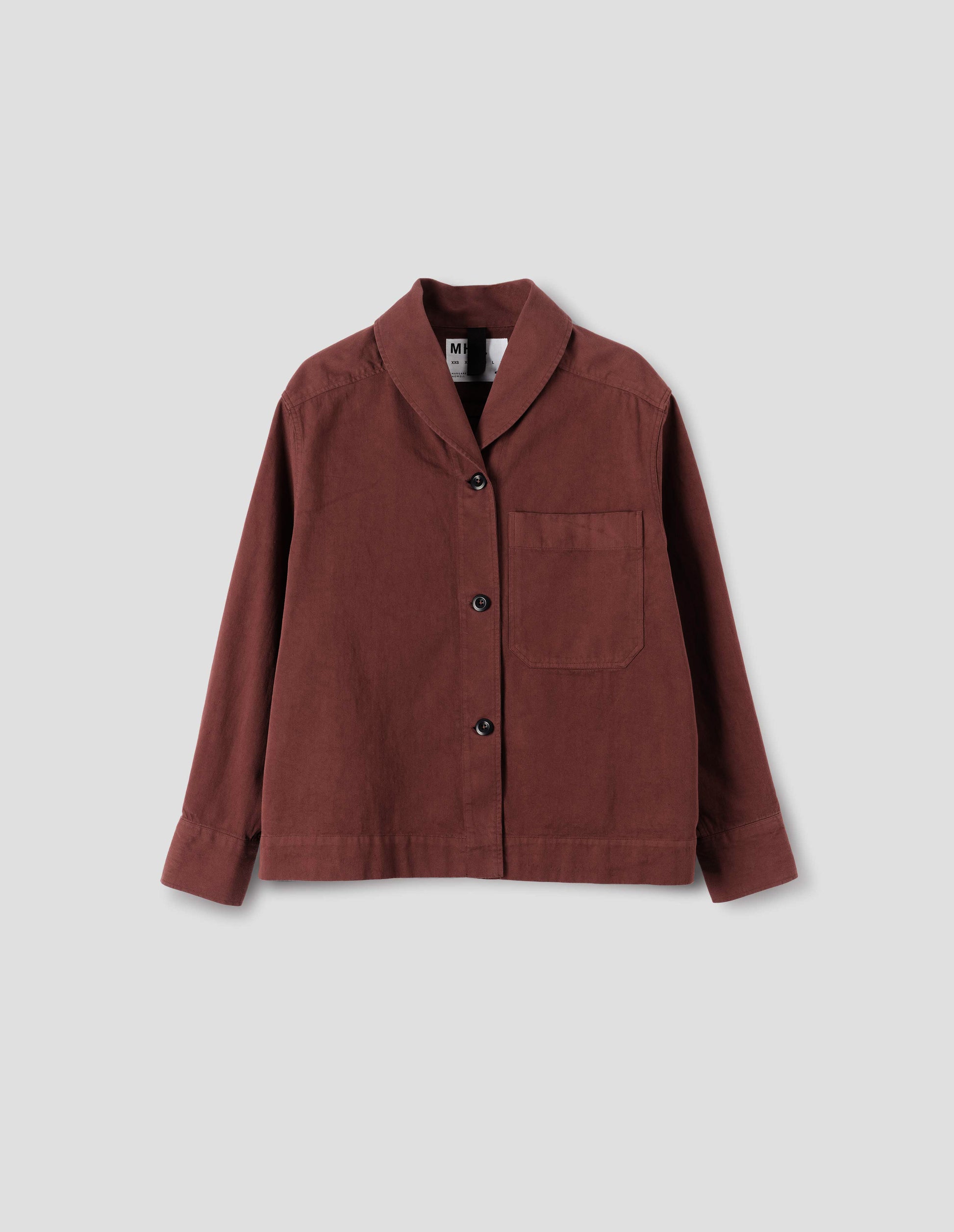 Reddish cotton shawl collar overshirt with dark buttons, a forward-positioned shoulder seam and a front patch pocket, front flat lay view.