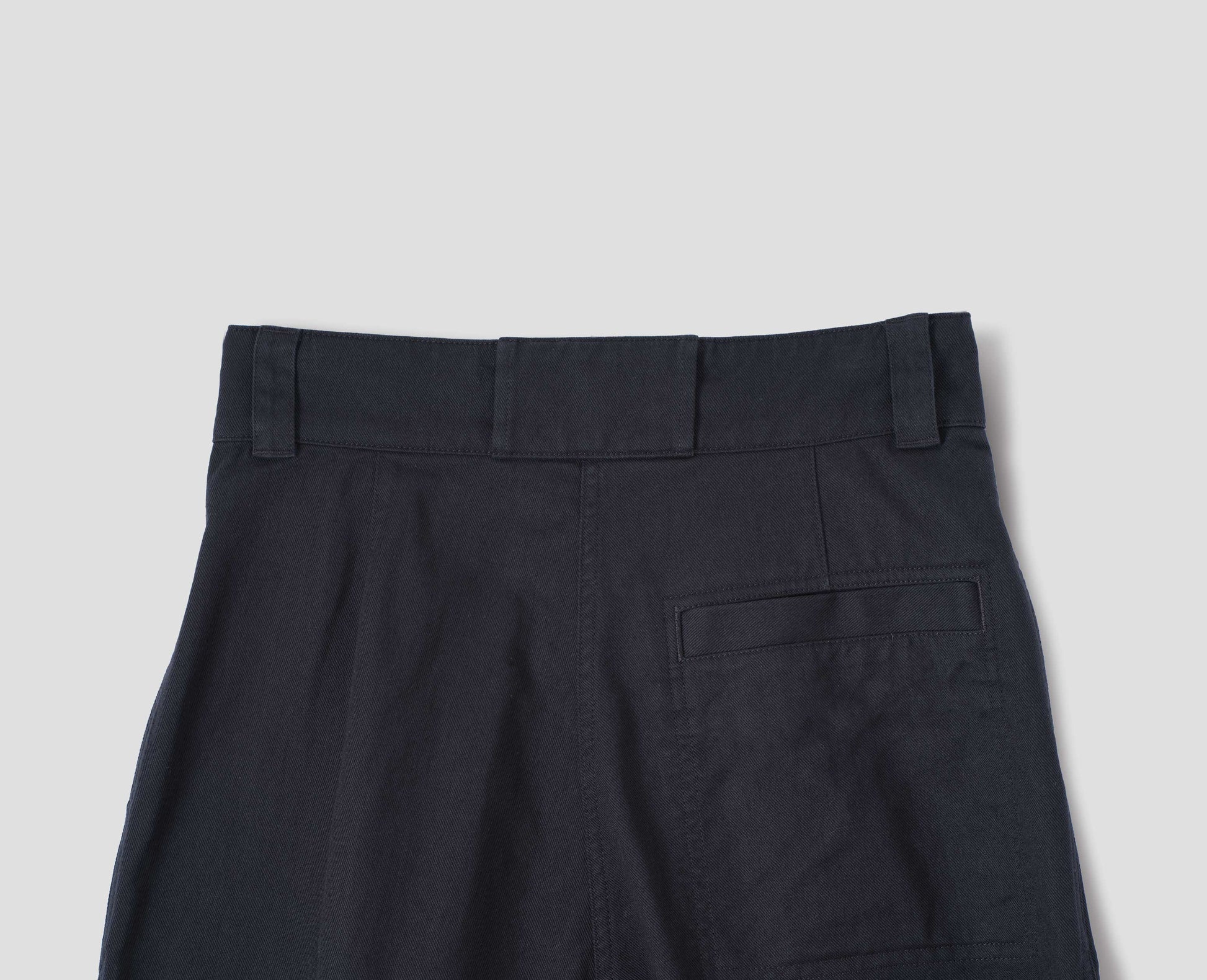Dark blue cotton trousers, with belt loops a single welt pocket, back flat lay view.