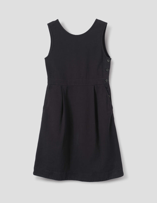 Black cotton dress, with side button fastening two pleats and slanted pockets, front flat lay view.