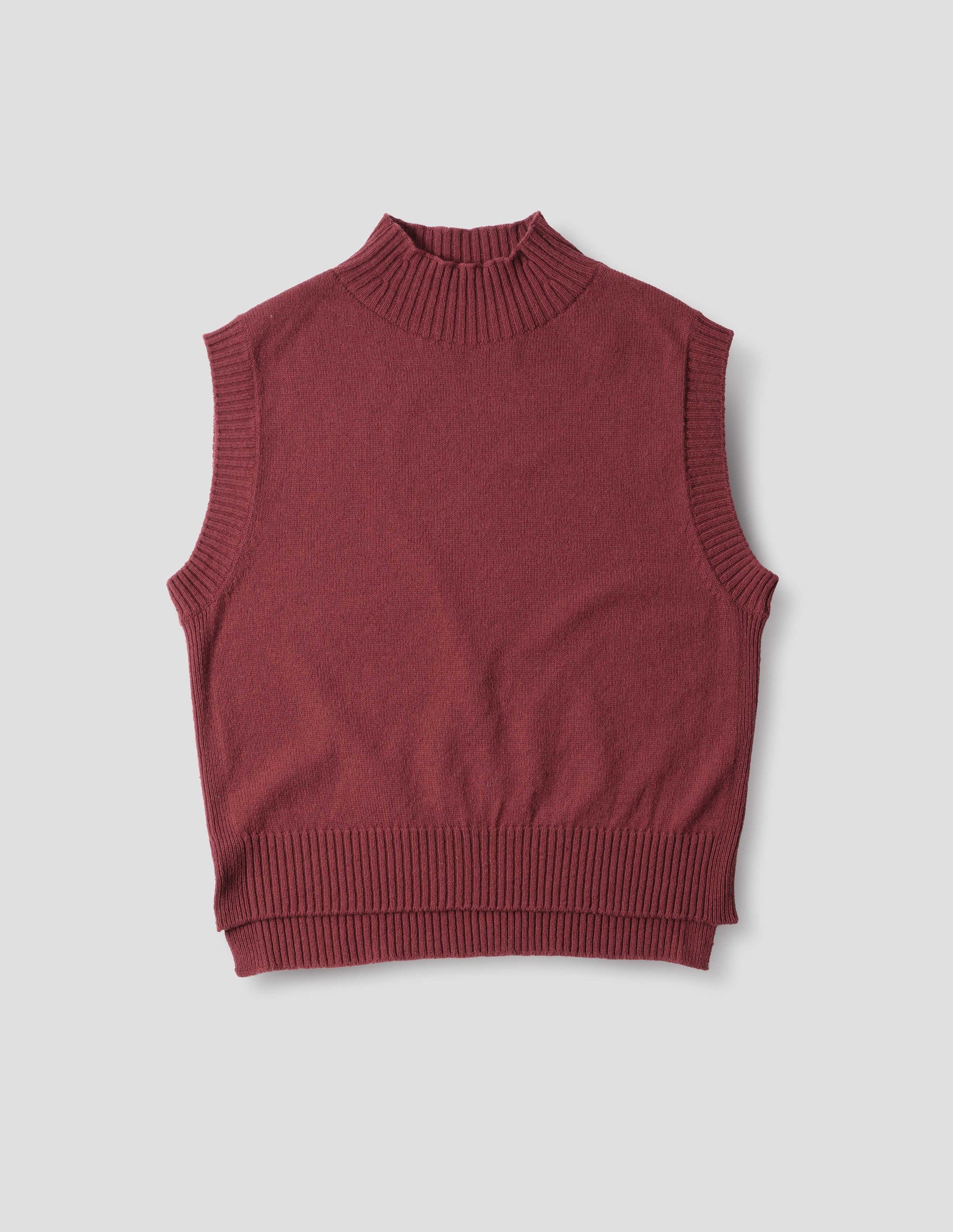 Reddish wool cotton slipover with a high rib neck, rib armholes and hem and split stepped hem, front flat lay view.
