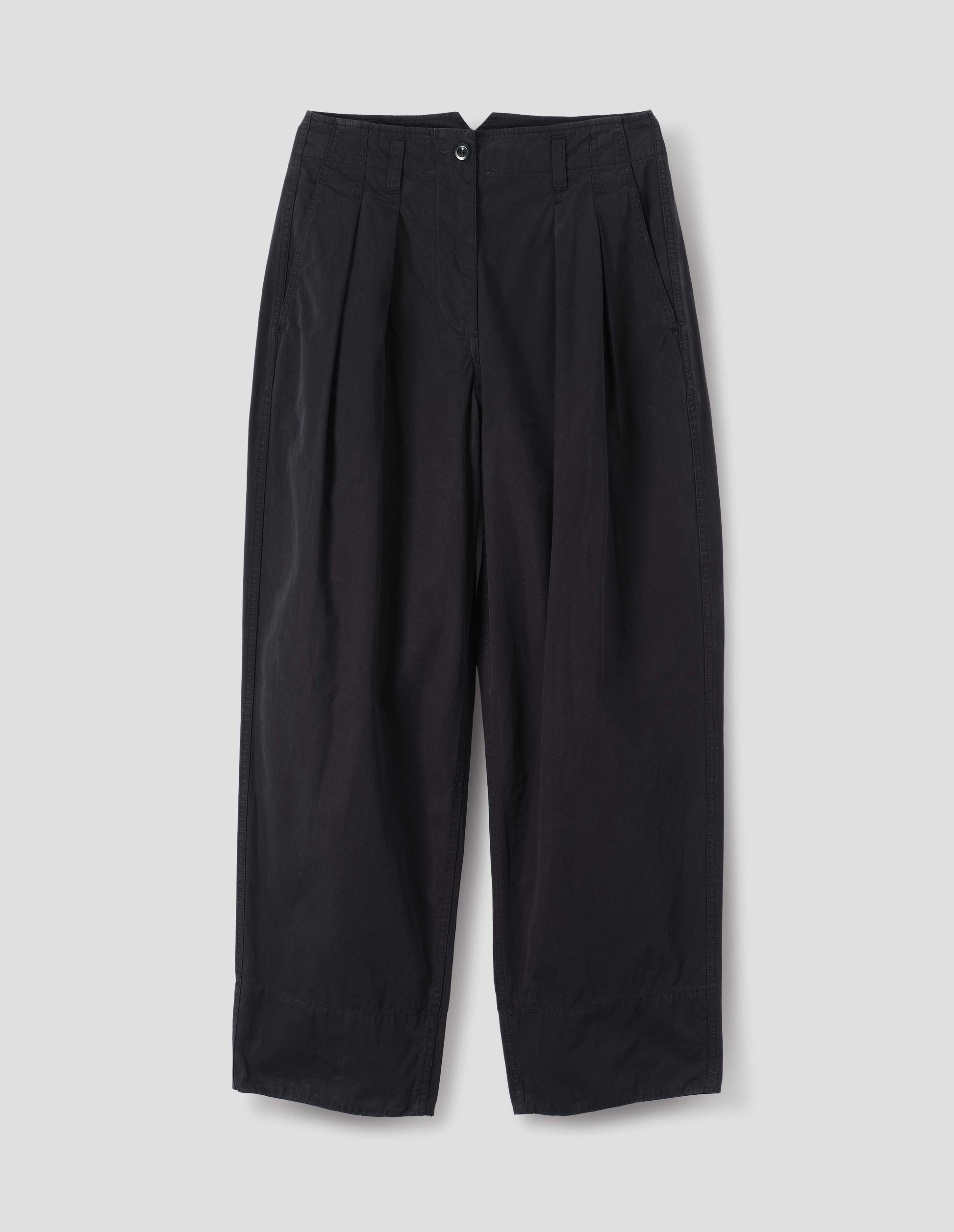 Black cotton trousers, with front pleats, a brown button with belt loops and side pockets, front flat lay view.