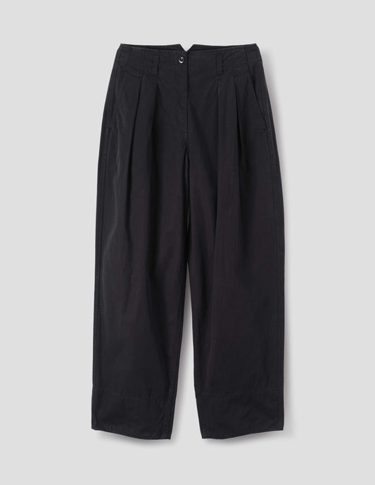 Black cotton trousers, with front pleats, a brown button with belt loops and side pockets, front flat lay view.