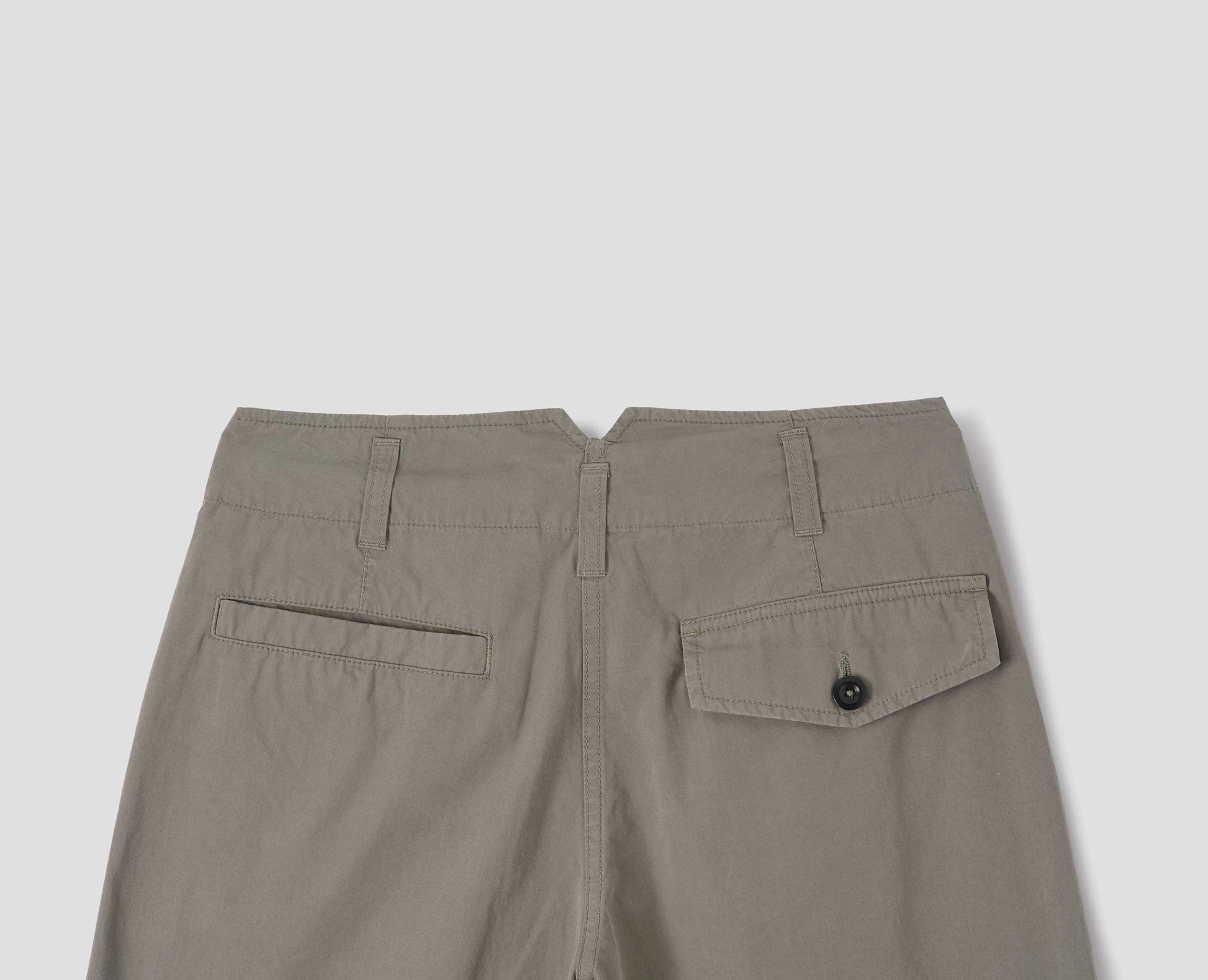 Greyish brown cotton trousers, with belt loops and V shape cutaway on waistband, one welt pocket and one button-fastening flap pocket, back flat lay view.