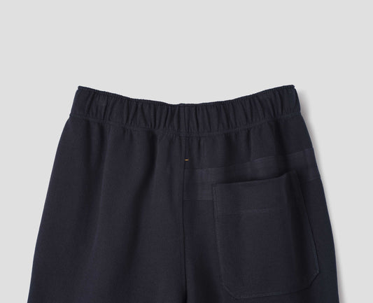 Dark navy lightweight jogger style trousers with back patch pocket and elasticated waistband, back flat lay view.
