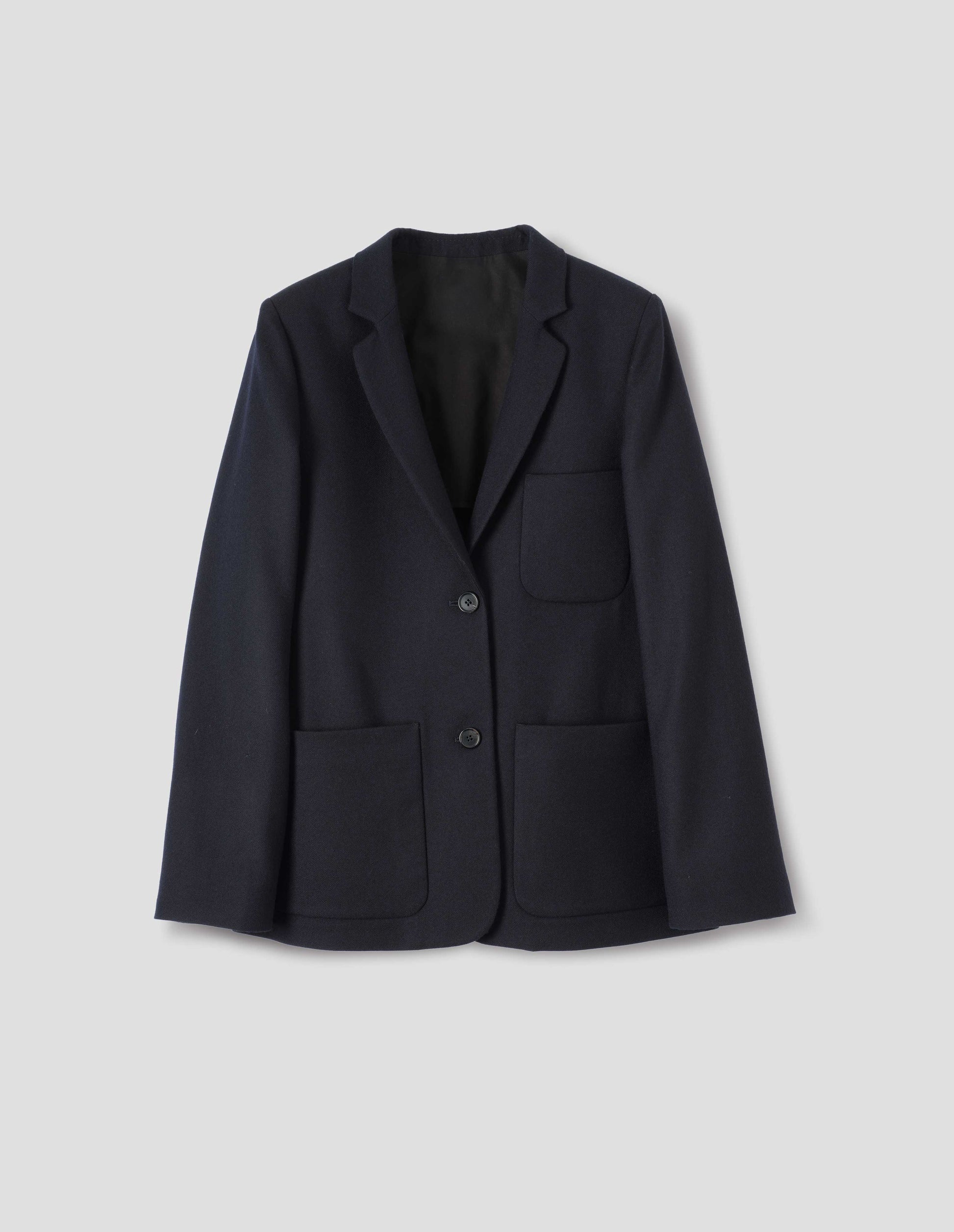 Dark blue wool blazer with narrow collar and horn button-through revere, three bluff patch pockets, rounded details on hem and pockets. Front flat lay view.