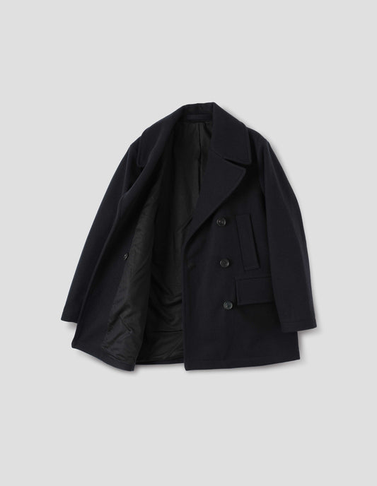 Dark blue cotton lined wool coat with large collar and revere, horn buttons, high-set single welt pockets and large flap pockets. Open flat lay view.