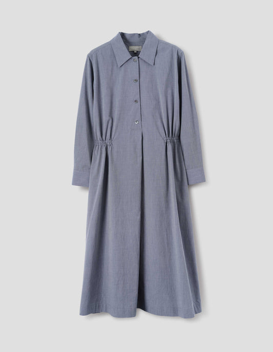 Blue cotton dress with collar, mother of pearls buttons on placket, long shirt sleeves, side pockets and externally applied channel at waist. Front flat lay view.