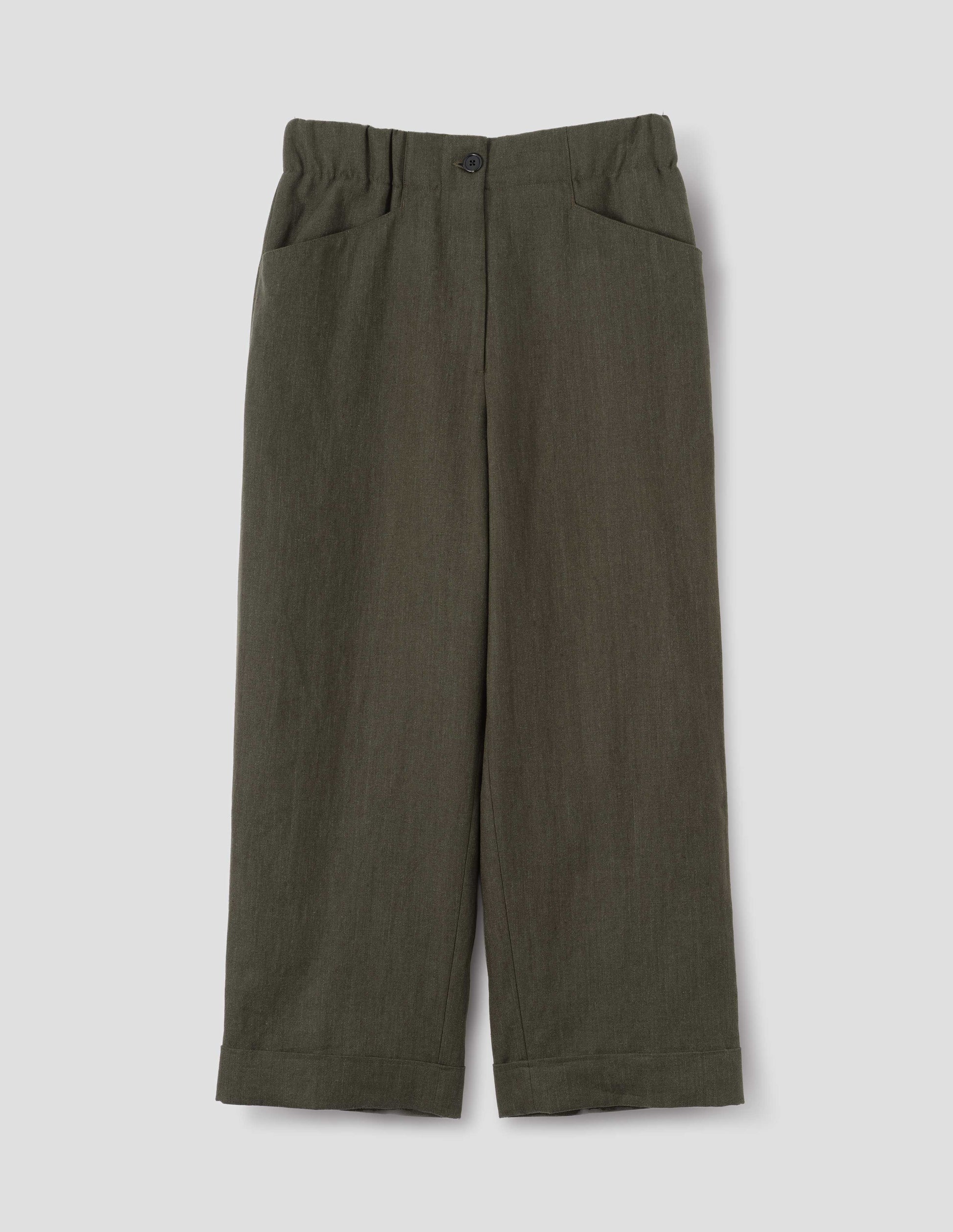 Dark green linen trousers with zip fly with horn button fastening on elasticated waistband, frog pockets and stitch-down turn-up hem. Front flat lay view.