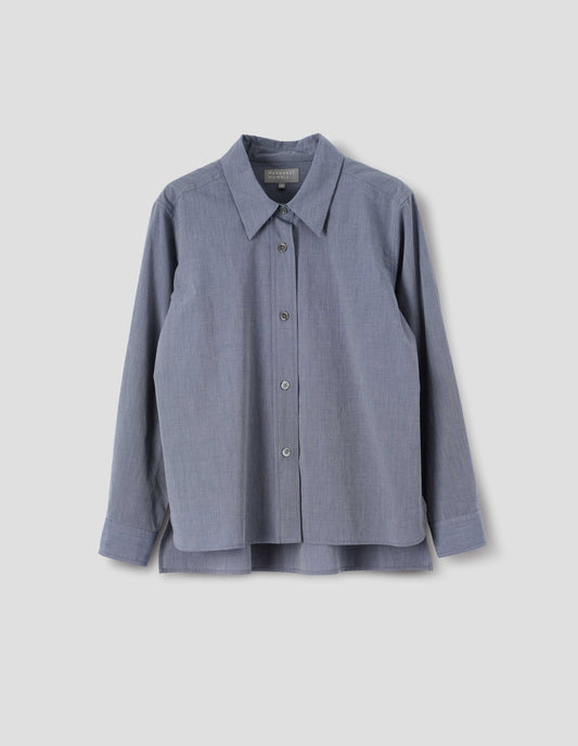 Blue cotton shirt with mother of pearl buttons on lipped placket, stepped hem with curved front and straight-cut back. Front flat lay view.