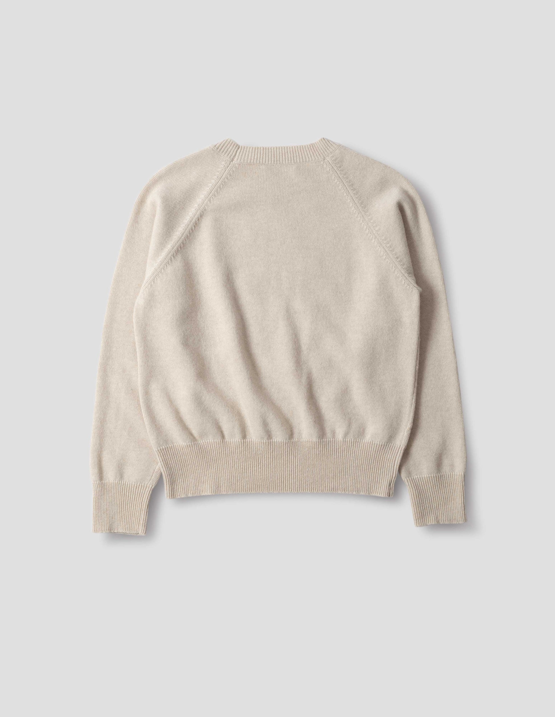 Light beige merino cashmere jumper with fully fashioned raglan sleeves with ribbed cuffs and ribbed hem. Back flat lay view.