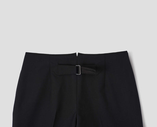Black wool trousers with cotton fine-binding waistband and cinch detail on back. Back flat lay view.