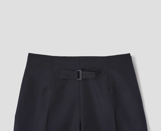 Dark blue wool trousers with cotton fine-binding waistband and cinch detail on back. Back flat lay view.