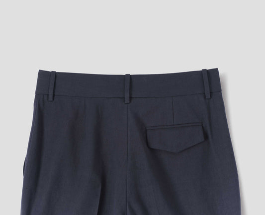 Dark blue cotton linen trousers with belt loops and concealed horn button-fastening flap back pocket. Back flat lay view.