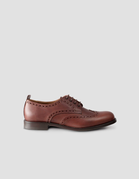 A single  brown leather brogue with heel pull detail and contrast leather lining. Side angle flat lay view.