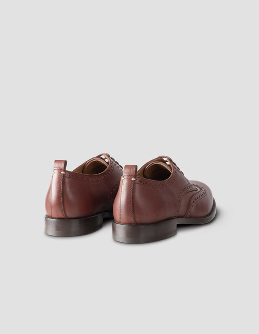 A pair of brown leather brogues with heel pull detail and contrast leather lining. Back flat lay view.