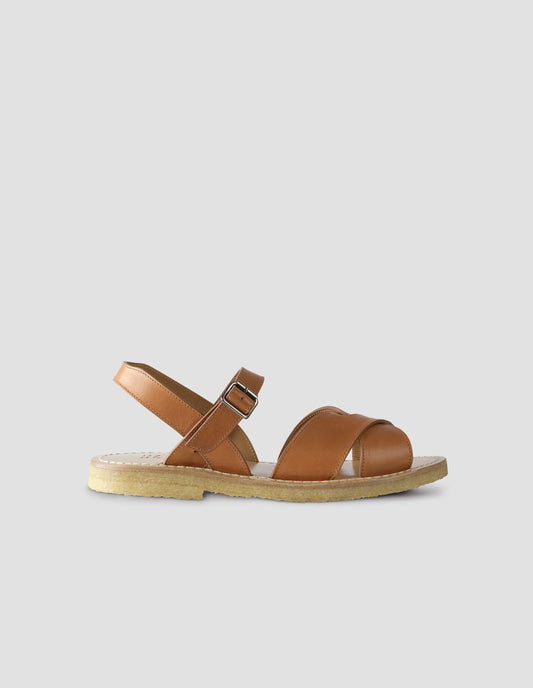 A single tan leather sandals with roller buckle fastening, contrast leather sole lining and crepe soles. Side view flat lay view.