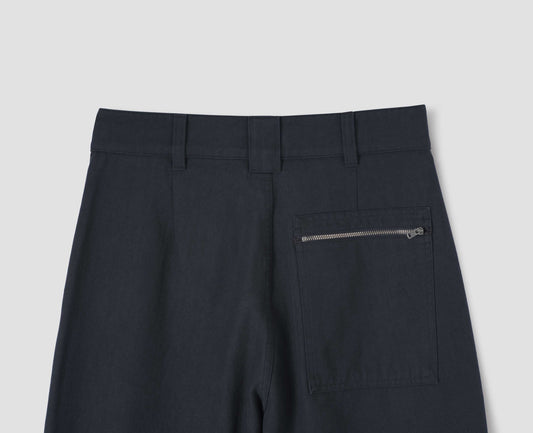 Dark blue trousers with three belt loops and zip patch back pocket, back flat lay view.