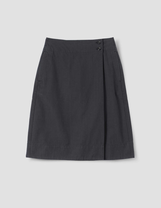 Dark blue wrap skirt with corozo brace button fastening and side pockets, front flat lay view.