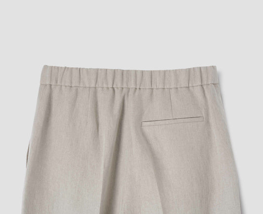 Beige trousers with welt back pocket and elasticated waist, back flat lay view.