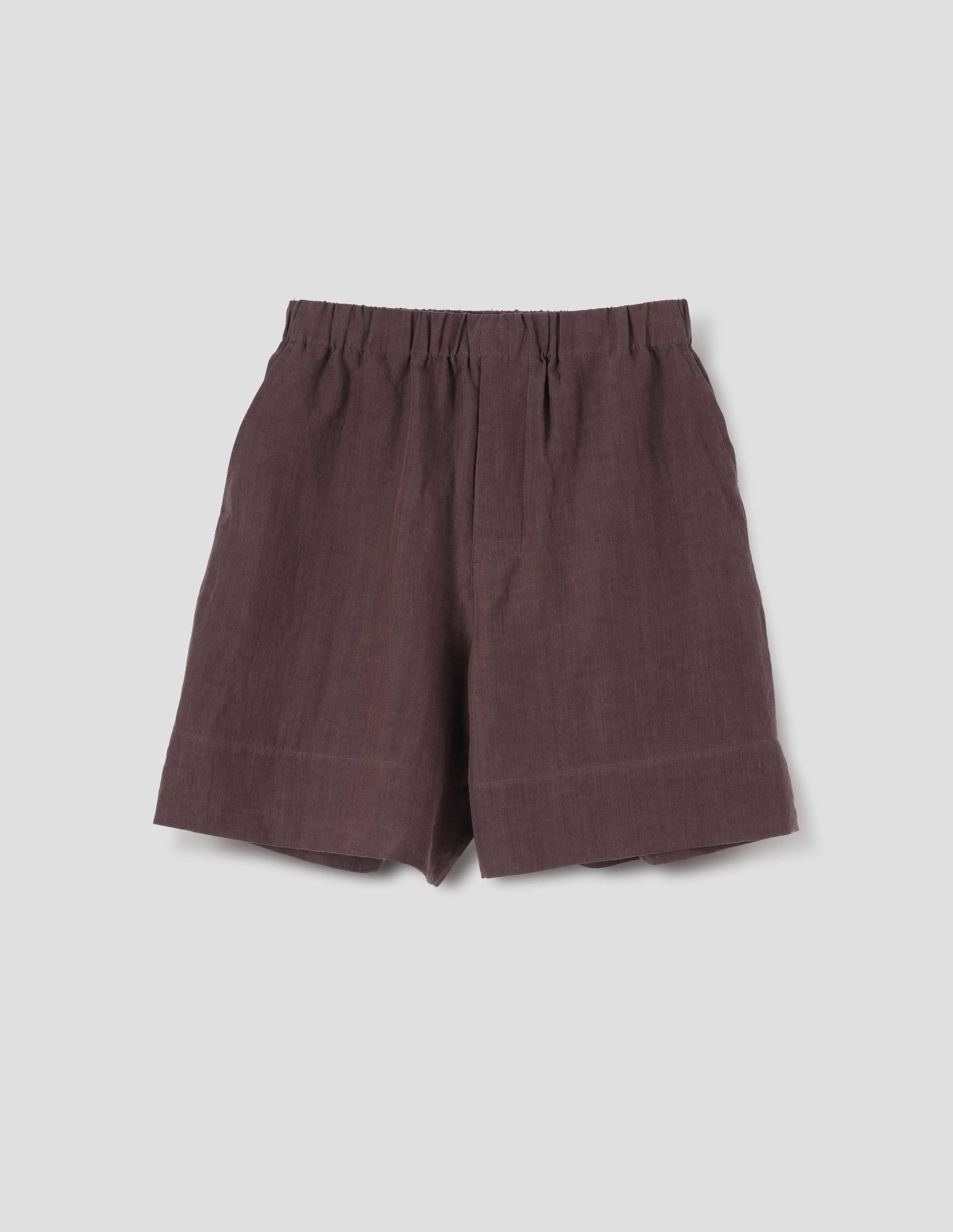 Reddish brown linen shorts, with elasticated waistband, side entry pockets and deep hem. Front flat lay view.