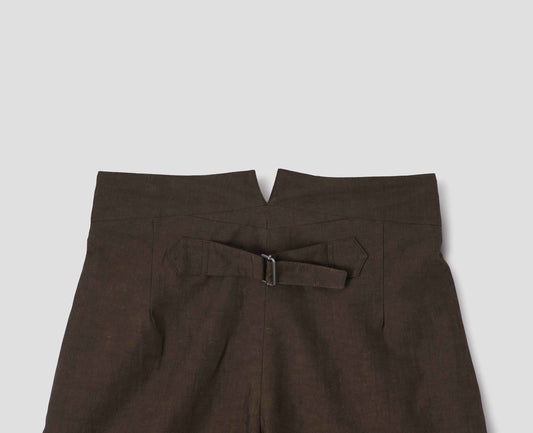 Brown cotton linen trousers, with deep waistband and cinch adjustor on centre back seam. Back flat lay view.