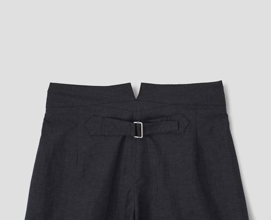 Black cotton linen trousers, with deep waistband and cinch adjustor on centre back seam. Back flat lay view.