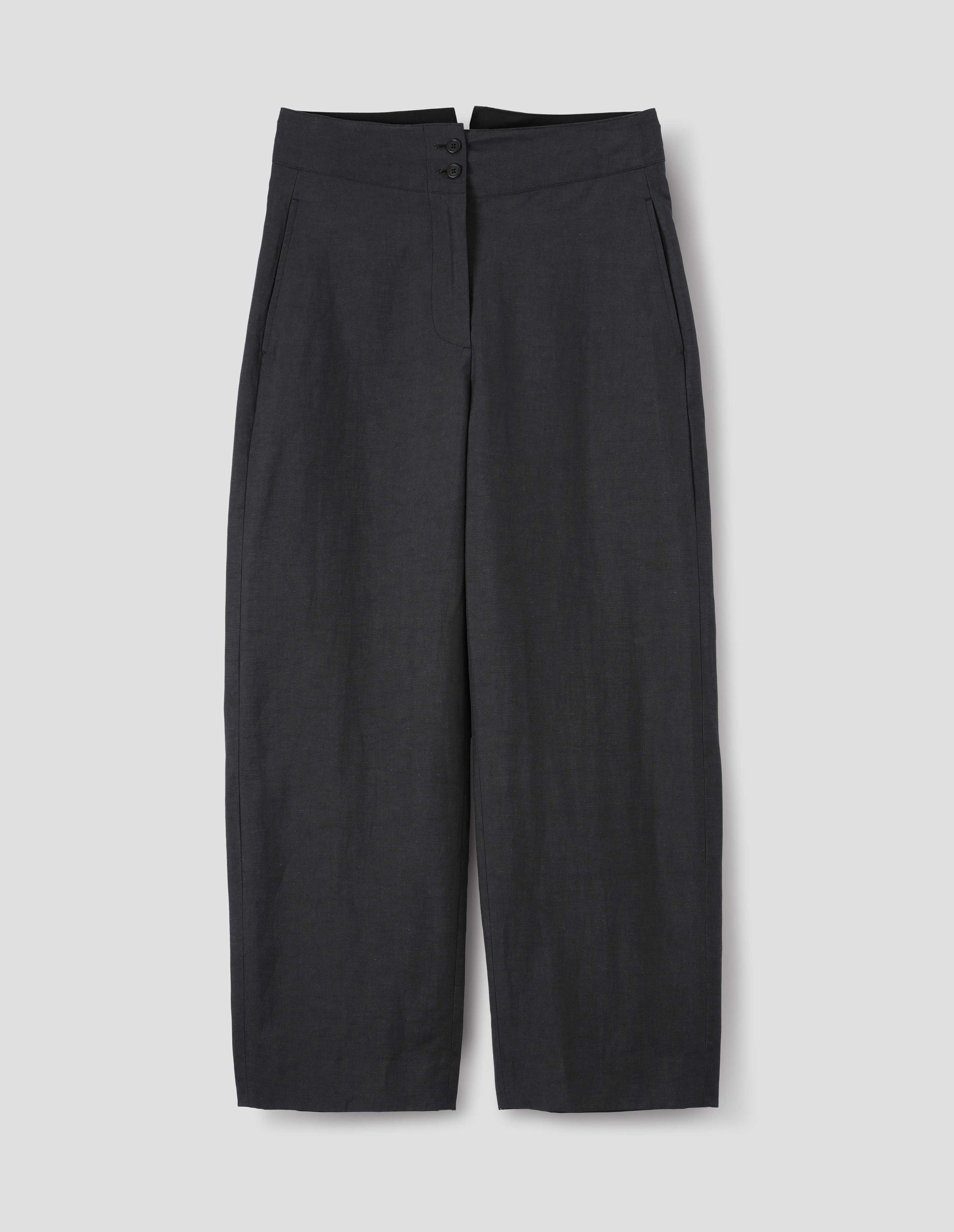 Black cotton linen trousers, with deep waistband, double horn button closure and slant side pockets. Front flat lay view.
