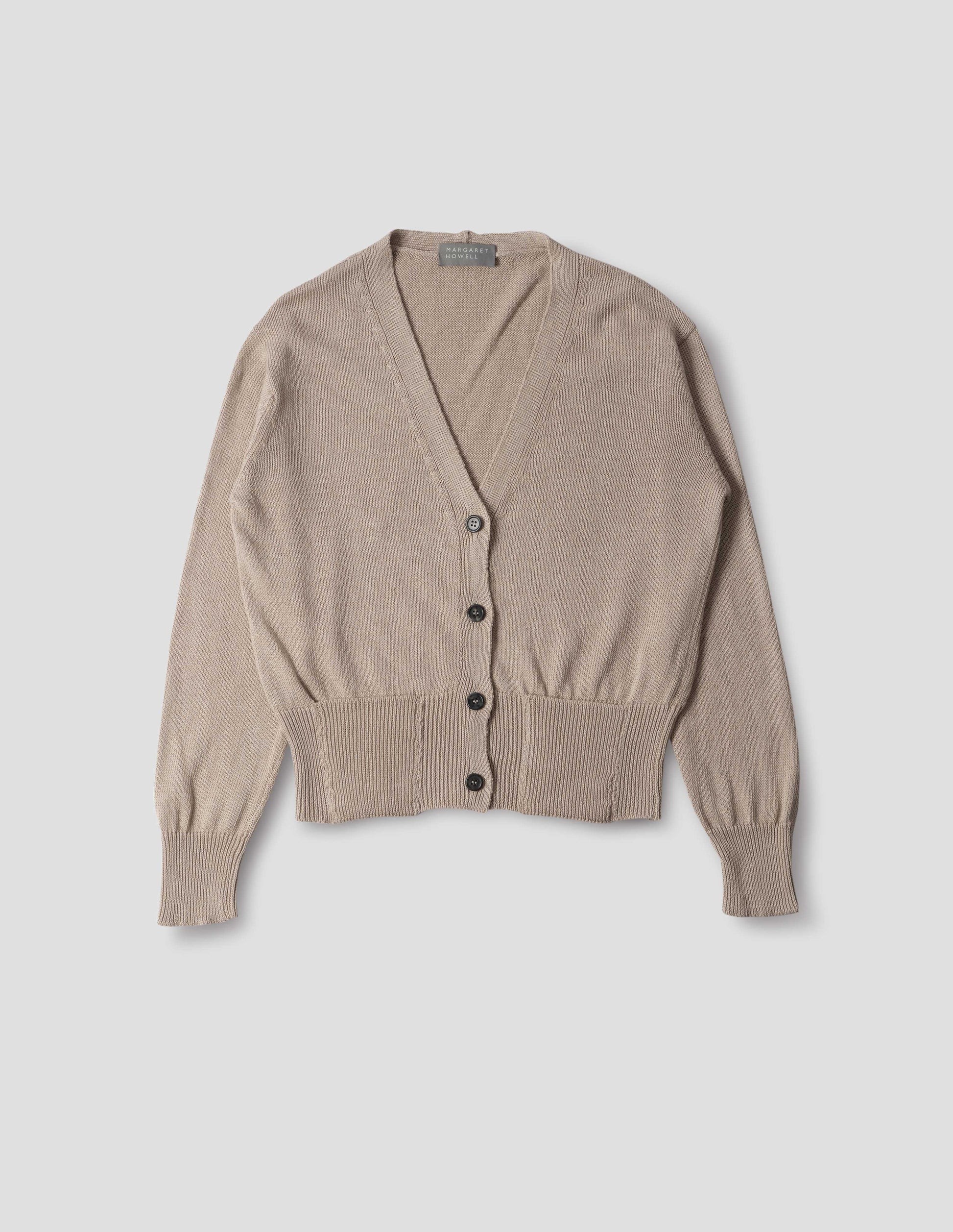 Beige linen cotton v neck cardigan with horn buttons, integral pockets and rib on neck, cuffs and wide hem. Front flat lay view.