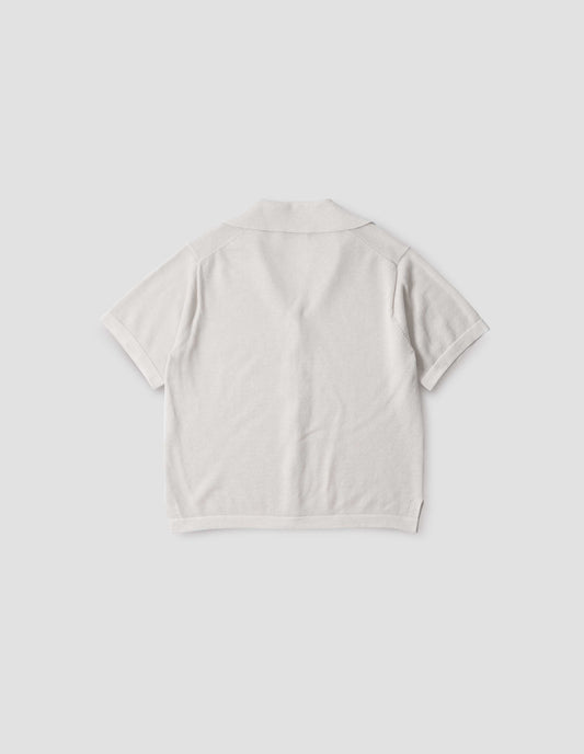 Off white knitted cotton short sleeve shirt, with fine gauge rib collar, placket, cuffs and side split hem. Back flat lay view. 