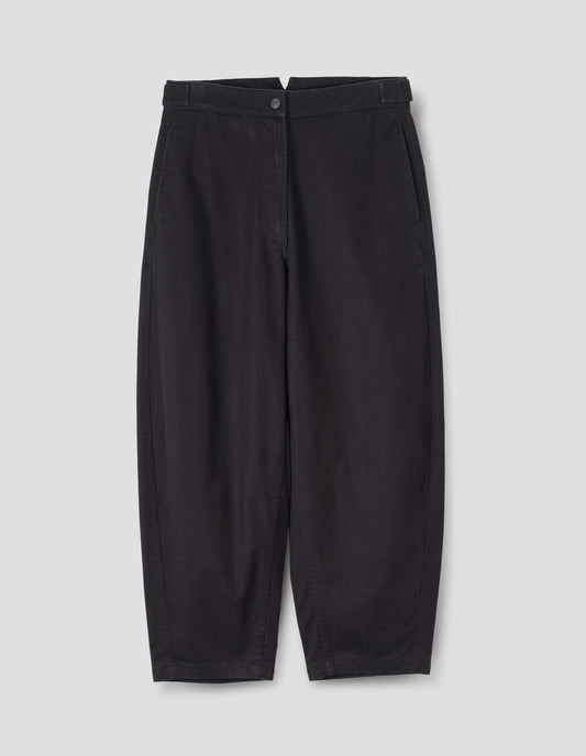 Indigo blue barrel leg trouser, with slant side pockets, silver metal closure and adjustable waist tab detailing. Front flat lay view. 