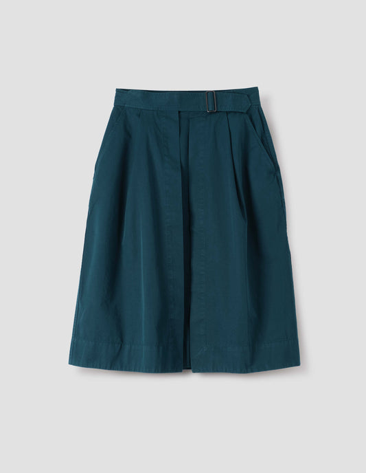 Greenish blue cotton twill skirt, with wide crossover waistband, button fastening slide adjuster and slant pockets. Front flat lay view.