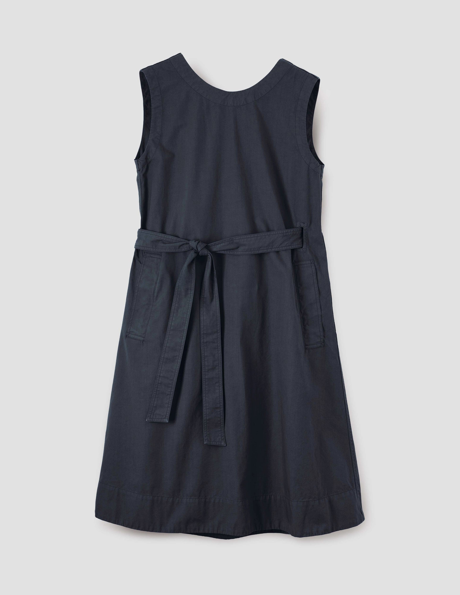 Dark navy cotton sleeveless dress with round neck, wrap around belt, side seam pockets and deep stitch hem. Front flat lay view.