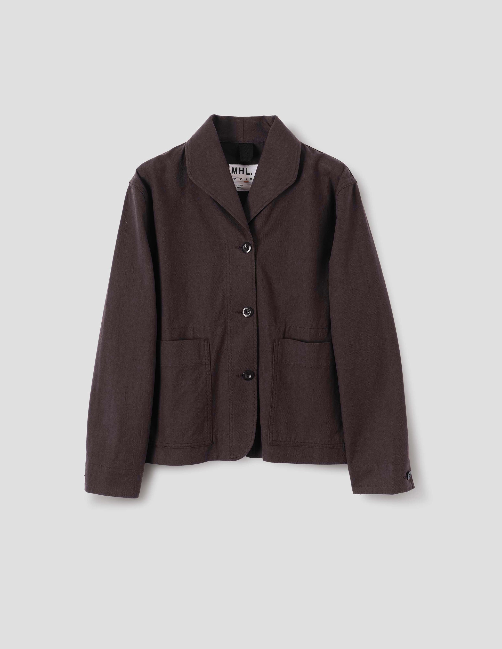 Dark brown cotton drill jacket with two patch pockets, corozo button closure and collar. Front flat lay view.