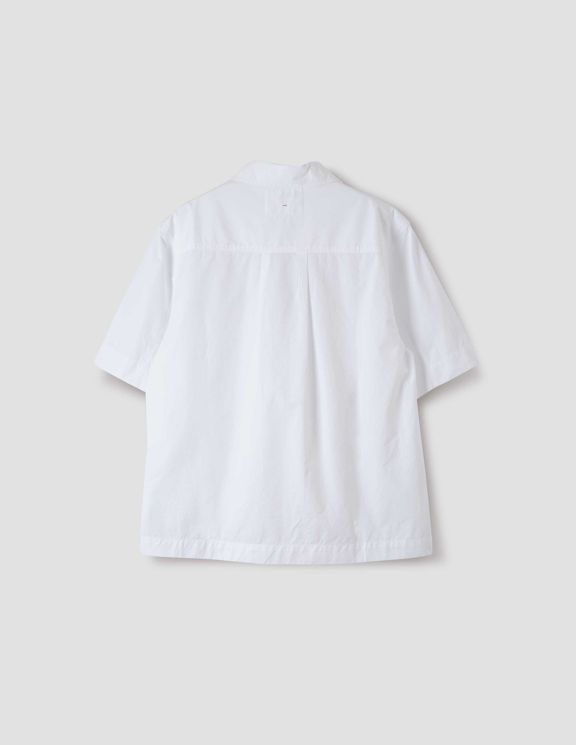 White short-sleeved shirt with side split hem and wide box pleat on back yoke. Back flat lay view.