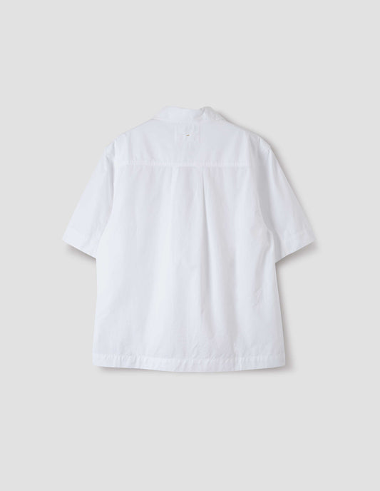 White short-sleeved shirt with side split hem and wide box pleat on back yoke. Back flat lay view.