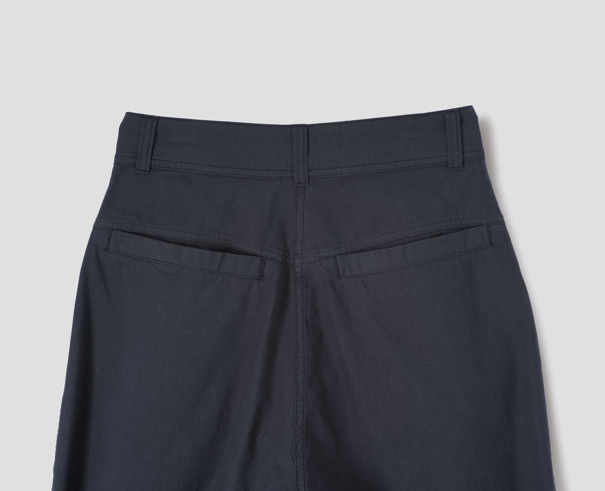 Dark navy wide leg pleated trousers, with high waist, belt loops and welt back pockets. Back flat lay view.