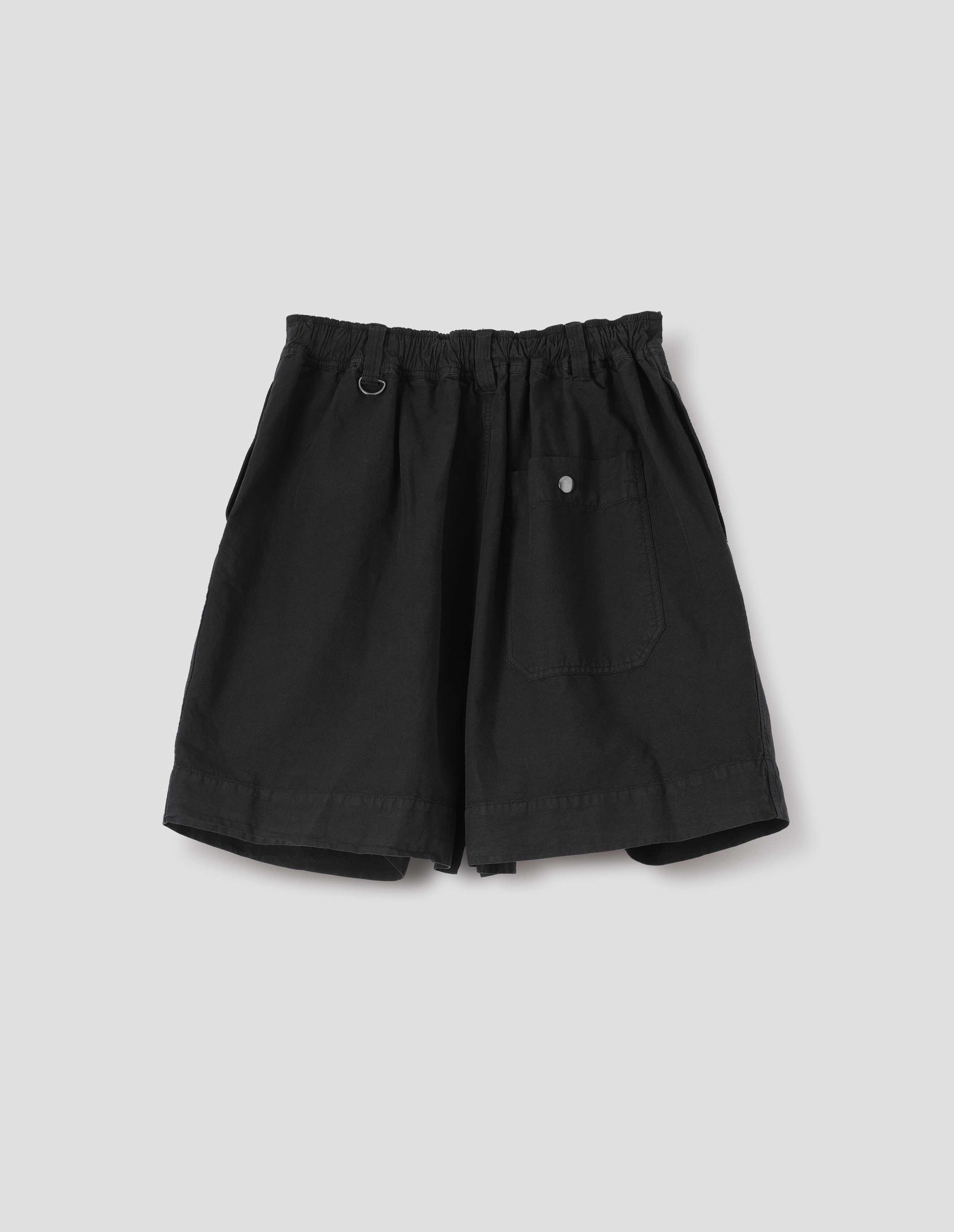 Black cotton linen shorts with elasticated waist, belt loops with one D-ring detail and press stud fastening on back patch pocket. Back flat lay view. 