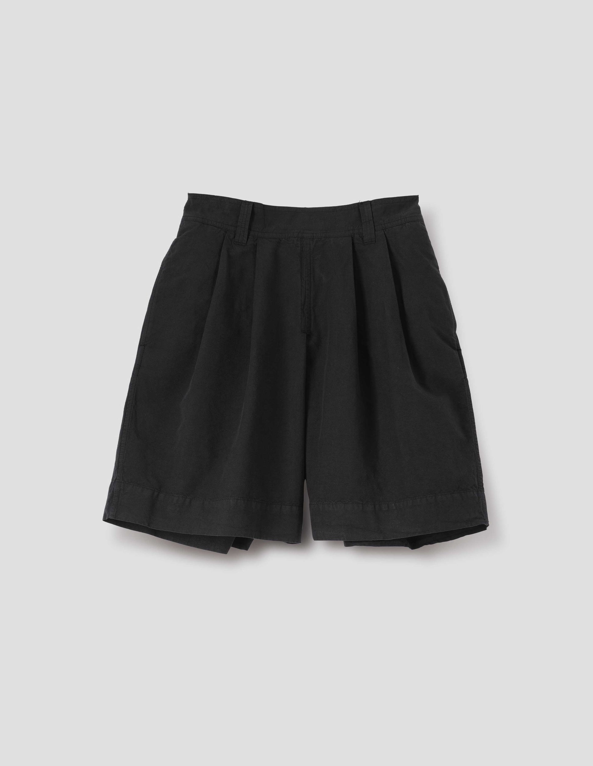 Black cotton linen shorts with pleated skirt front panel, semi-elasticated waistband, side pockets, and belt loops. Front flat lay view.