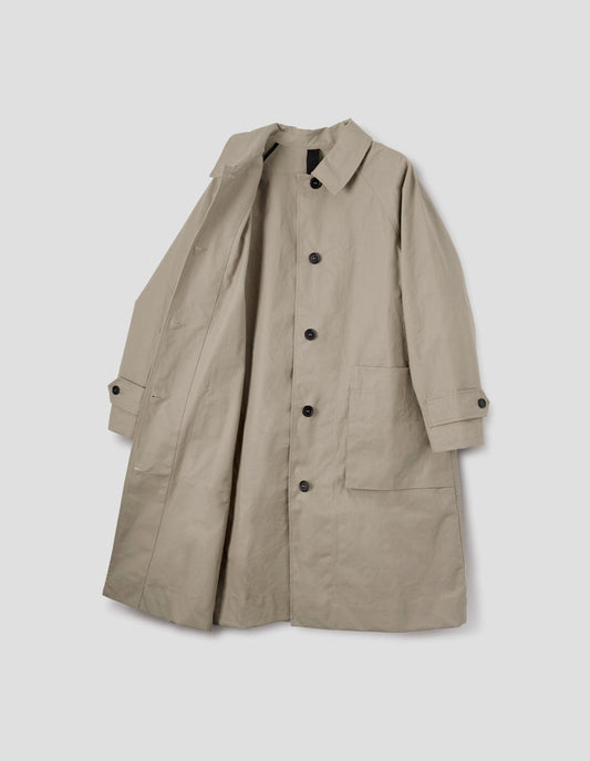 Beige cotton canvas long sleeve mac, with storm tab fastening neck, raglan sleeve, button tab adjustable cuffs and large patch bellow pockets. Front flat lay open view.