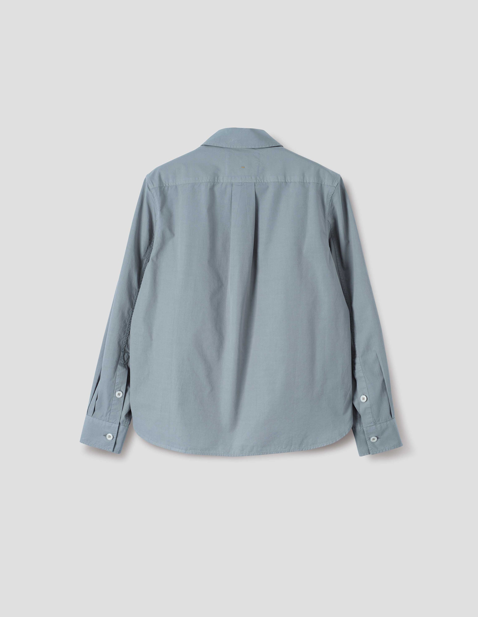 Grey regular cut shirt with box pleat on back yoke, corozo button cuffs and curved hem. Back flat lay view. 