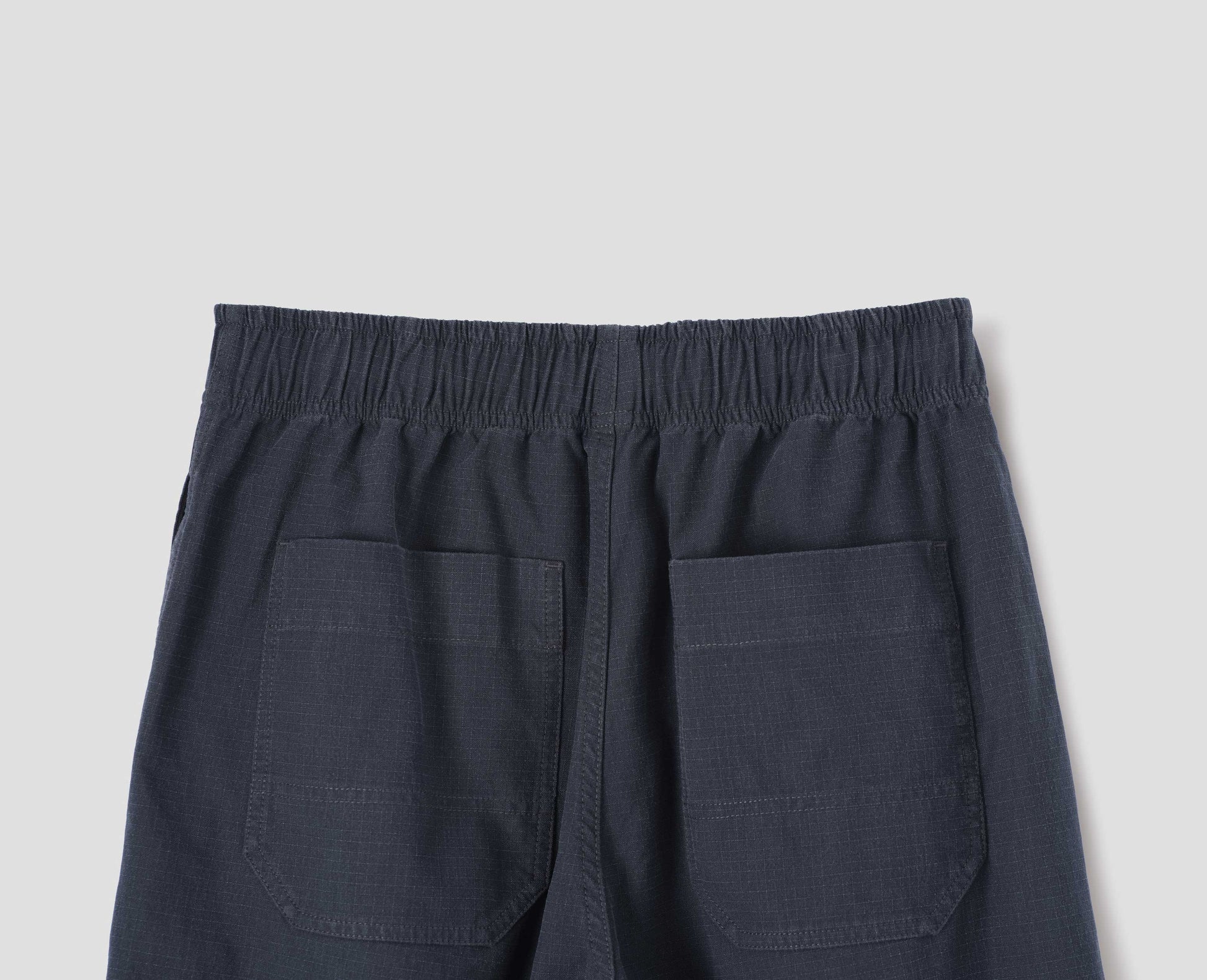 Dark navy blue joggers with elasticated waistband and patch back pockets. Back flat lay view.