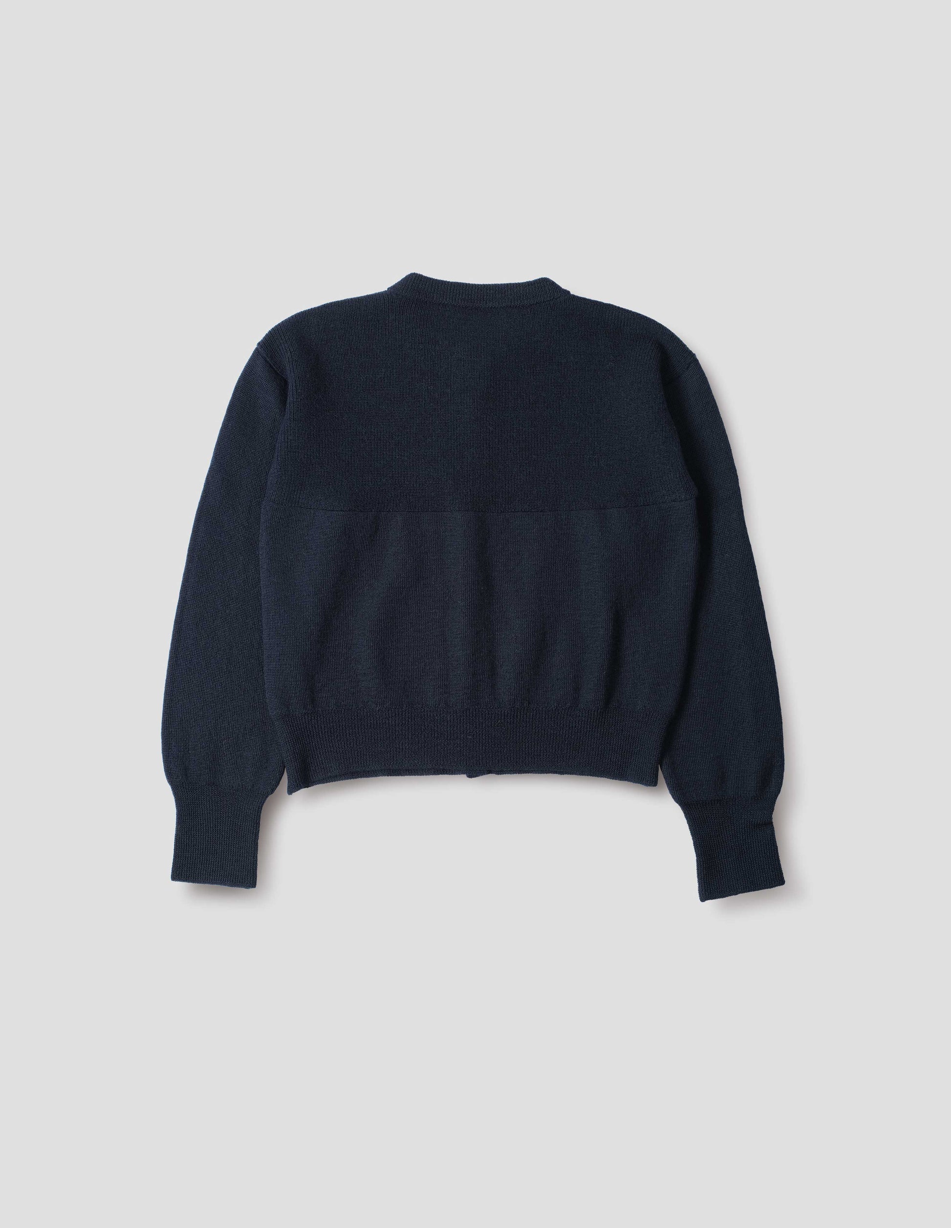 Dark navy blue wool textured cardigan, with contrast panel across upper back and rib detailing on neck, cuffs and hem. Back flat lay view. 